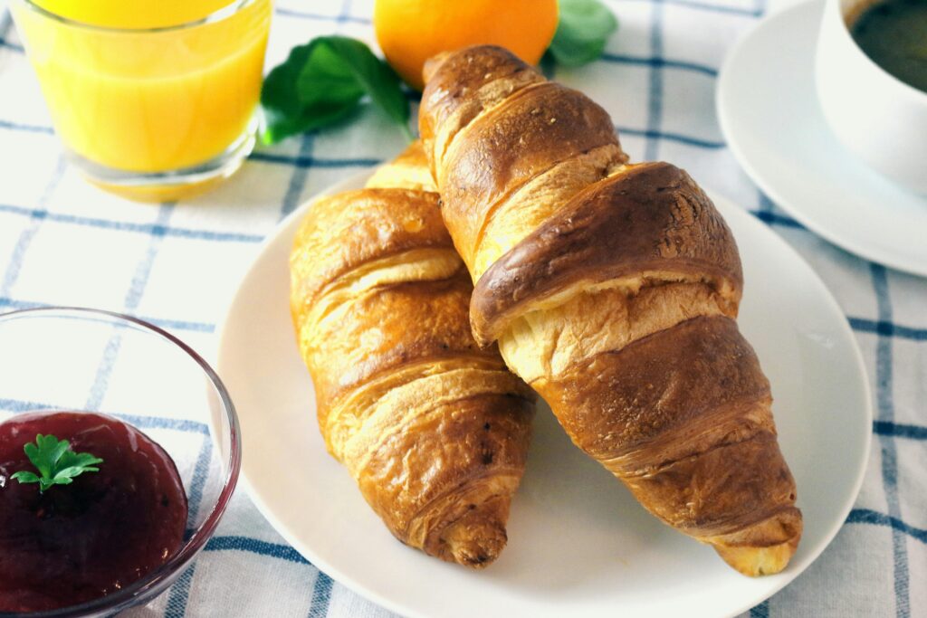 Tasty croissants served with orange juice and jam for a perfect breakfast.